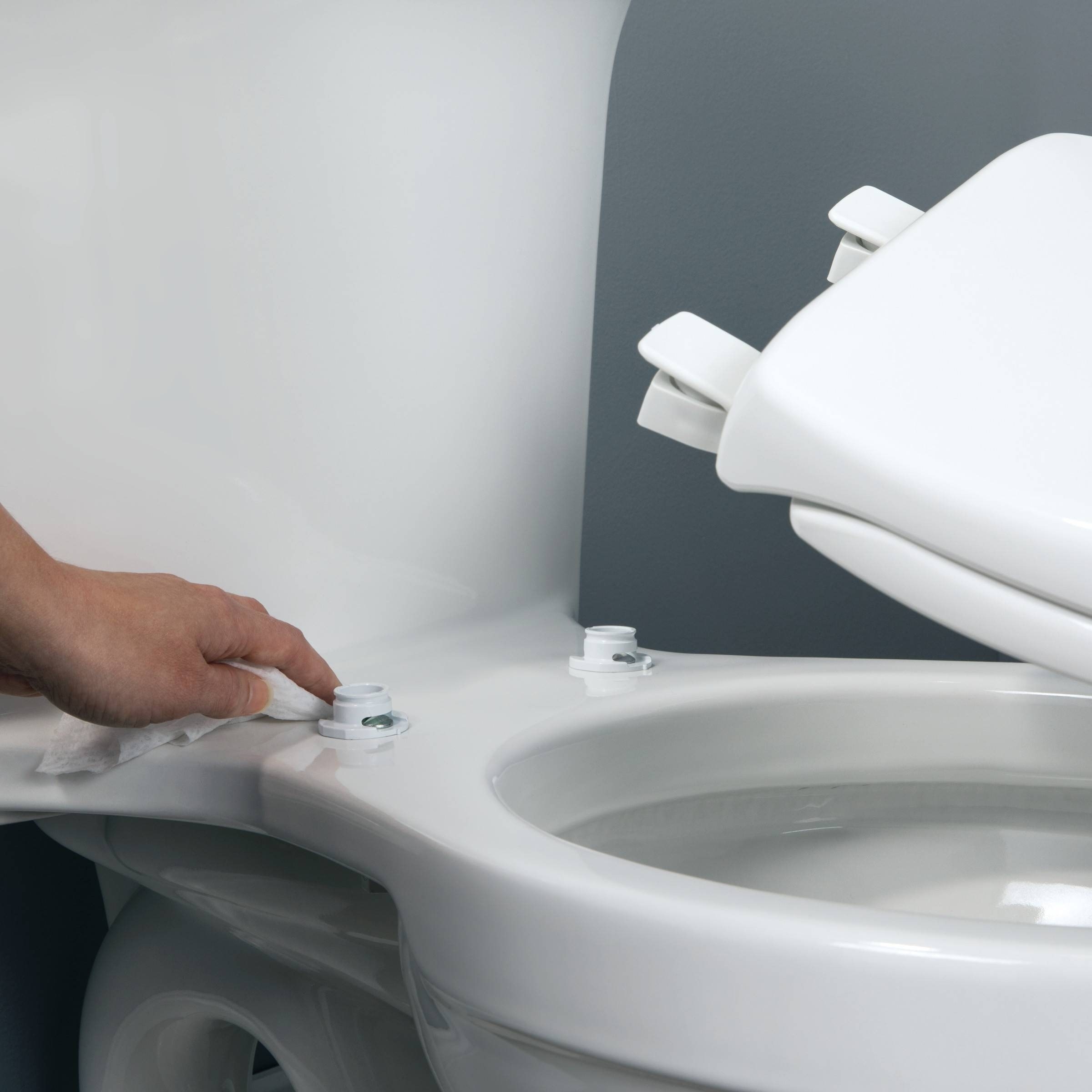 a hand installing the new toilet seat