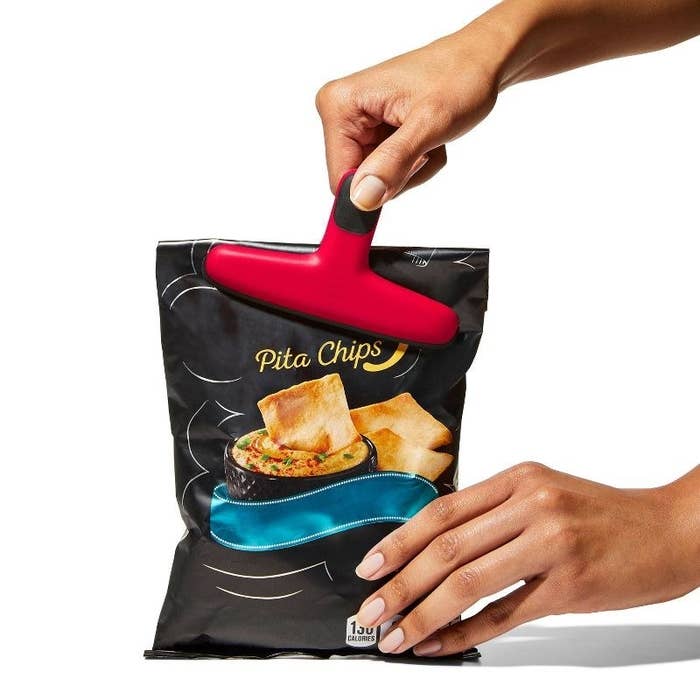 hands using the red clip to close a bag of pita chips