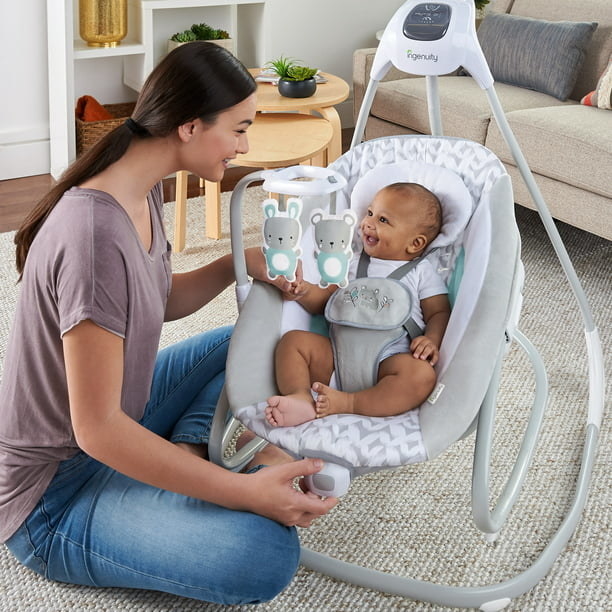 A model parent smiling at a model baby in the swing
