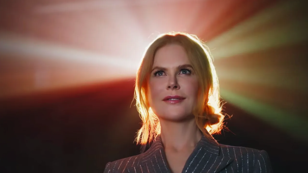 Kidman smiles at the screen as beams of light from the movie projector illuminate the back of her head