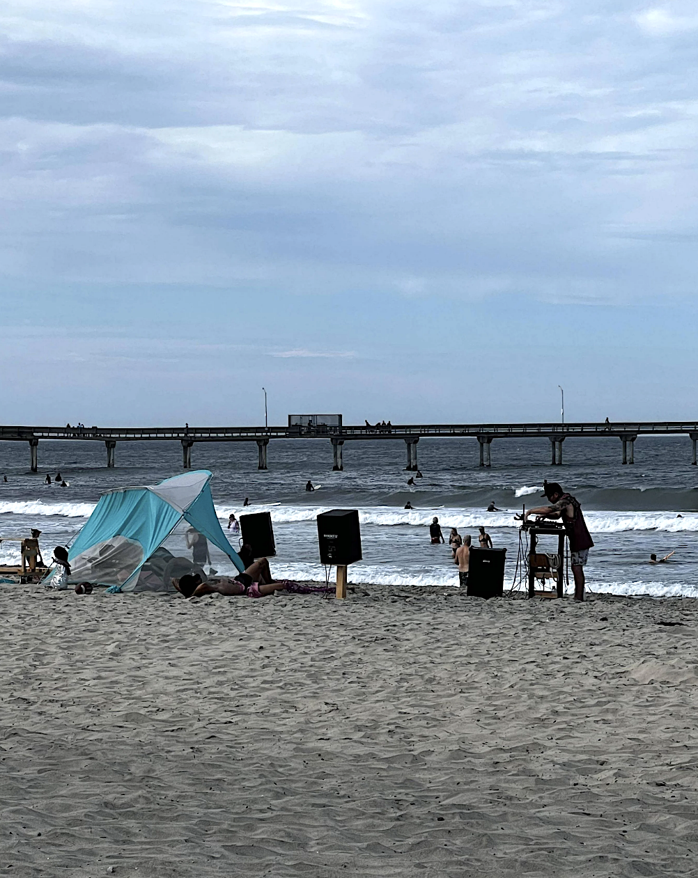 A DJ with speakers on a sandy beach