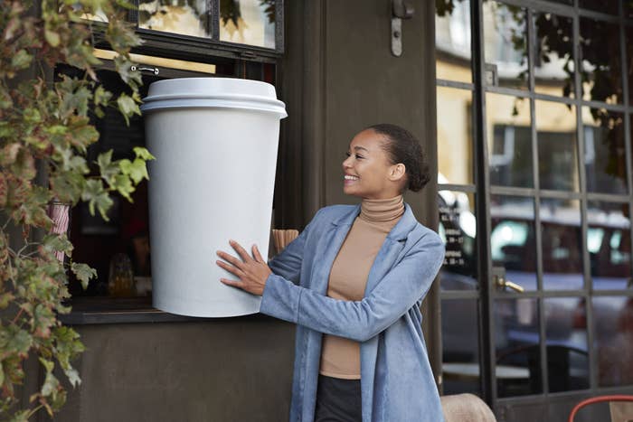 happy young woman holding a giant coffee cup
