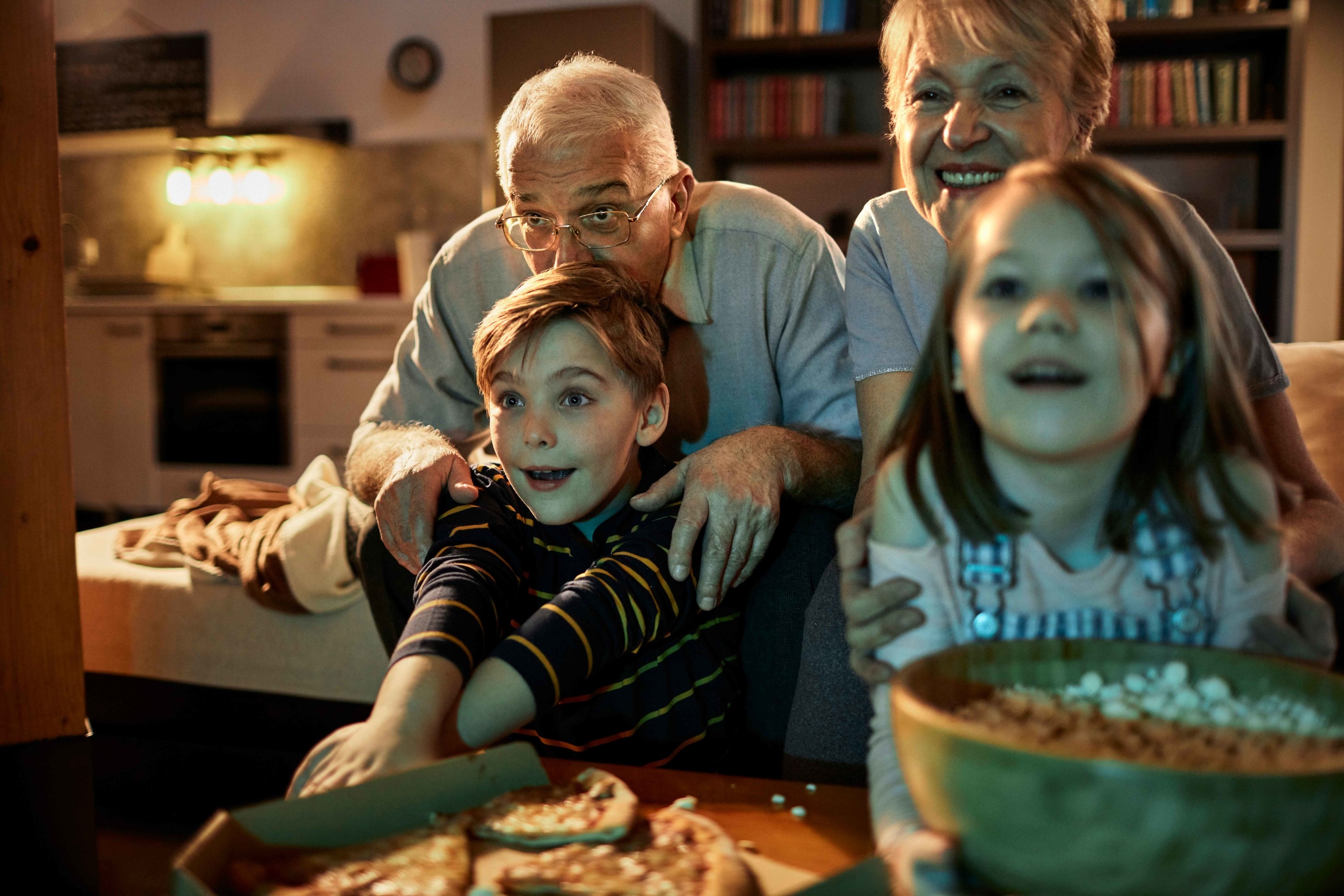 Grandparents watching a movie with their two grandchildren