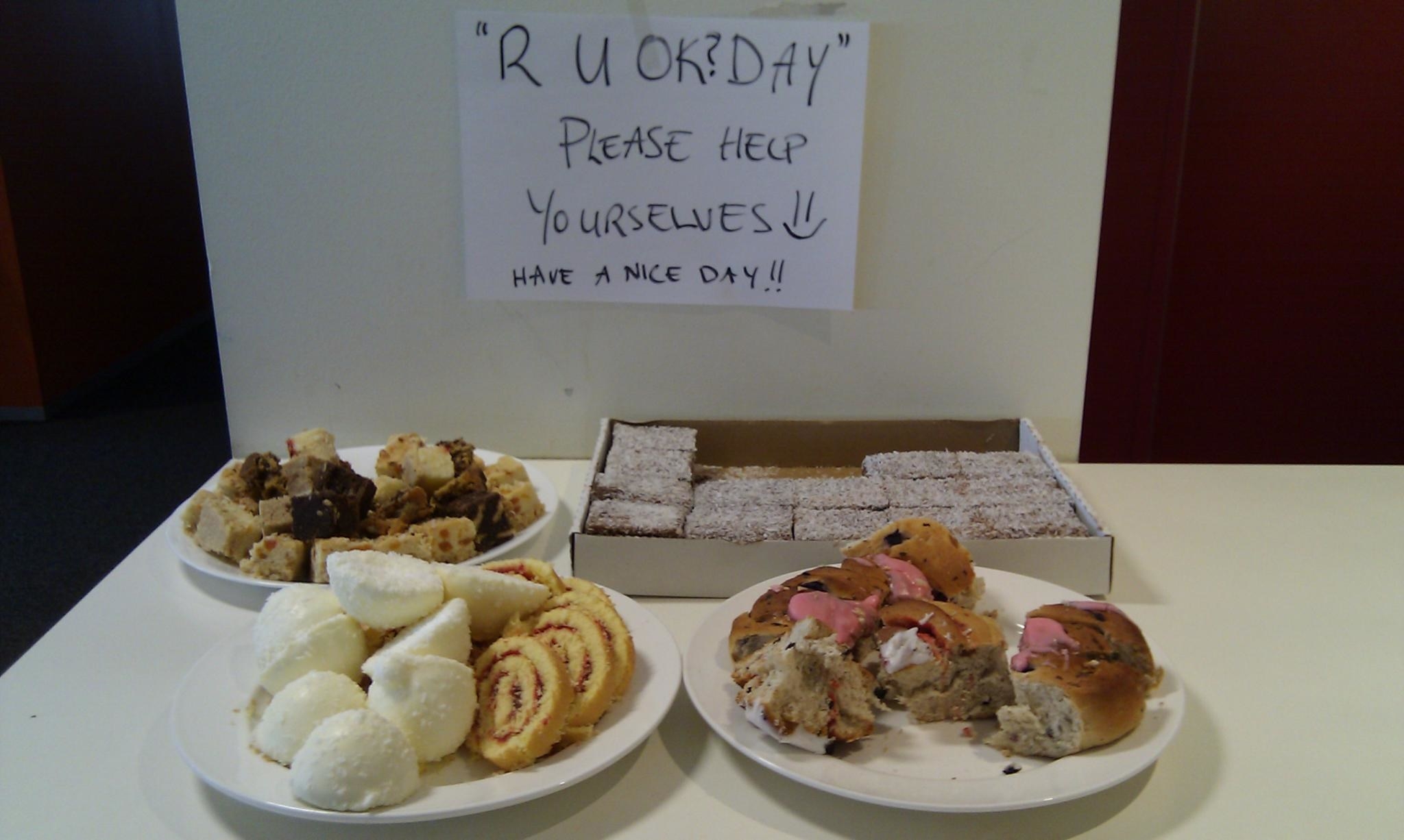 A table laid out with baked goods; there is a sign saying &quot;R U OK day, please help yourselves! Have a nice day&quot;