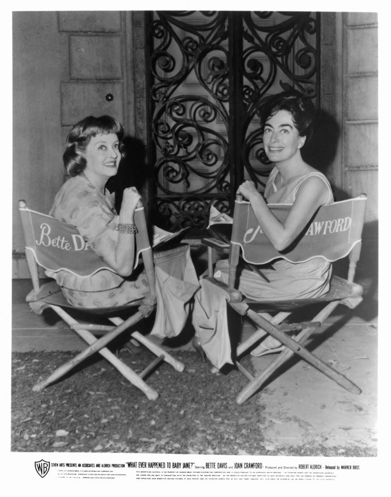 Davis and Crawford looking back at the camera as they sit on set