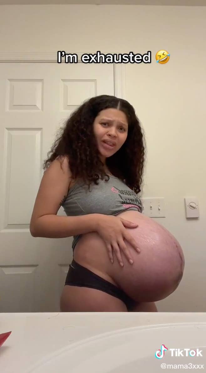 Danisha looking at her baby belly in the mirror with the caption &quot;I&#x27;m exhausted&quot;
