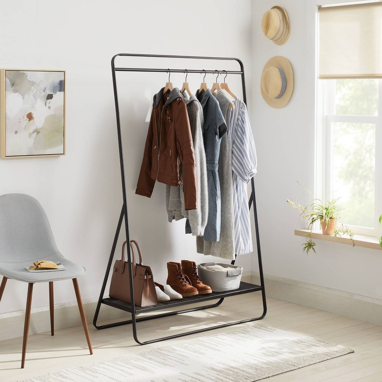 The garment rack in a room with clothes hanging and shoes on the bottom