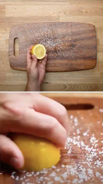 hand rubs lemon half over salt-covered wood cutting board