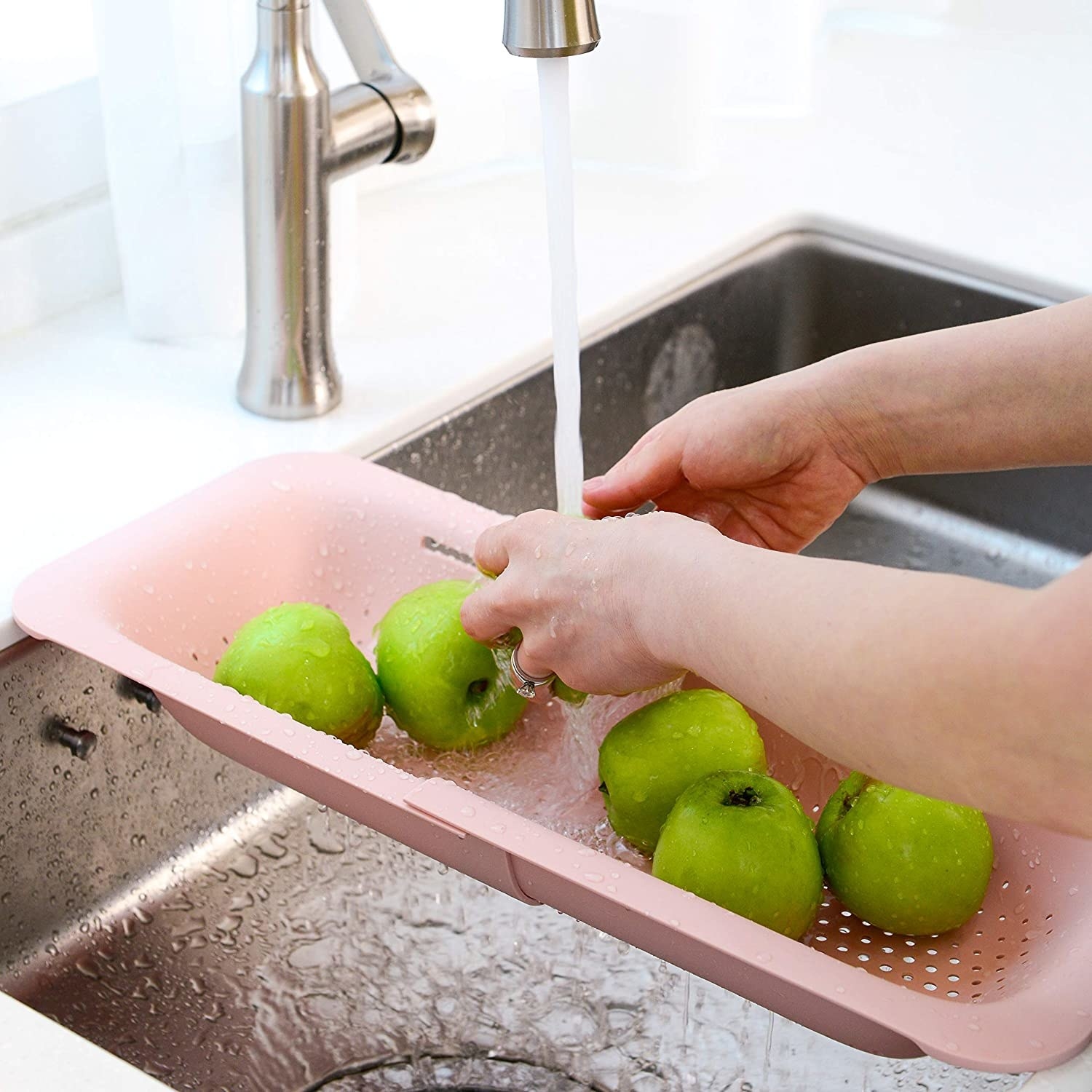 a person using the extendable strainer over the sink