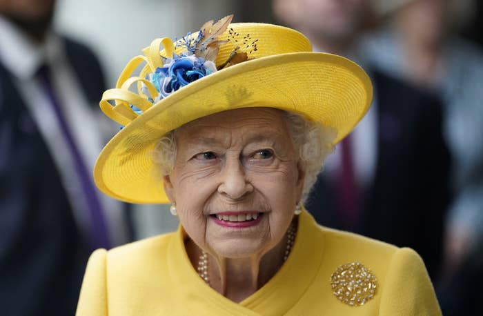 Close-up of the Queen smiling and wearing a yellow hat