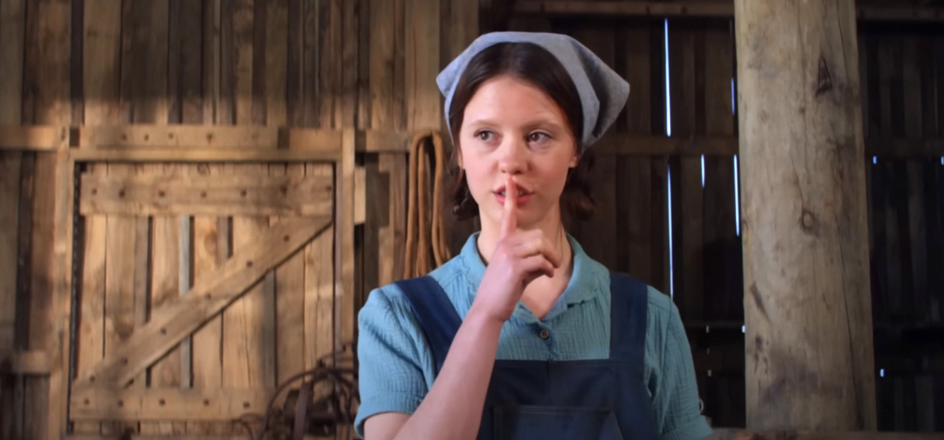 Mia Goth dressed as a farmgirl with overalls and a scarf on her head