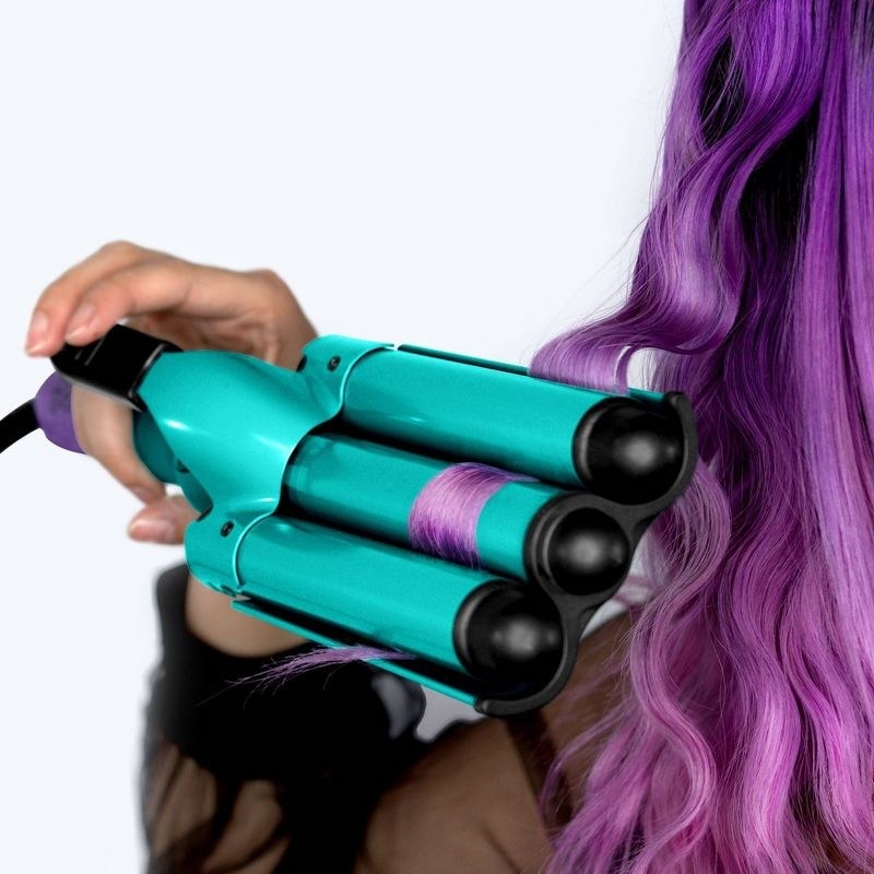 A person with purple hair using a heated wave tool