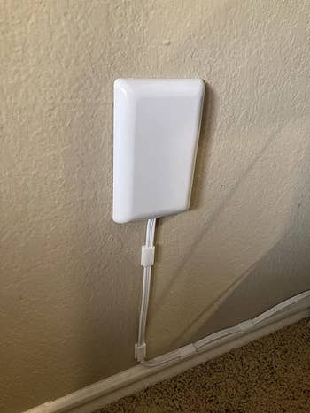 after: the socket, now with the powerstrip, plugged into the wall with the cord running along out of sight thanks to cord clips