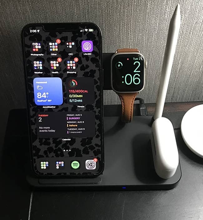 A charging station with a reviewer's iPhone, Apple watch, AirPods, and Apple pencil all charging at the same time