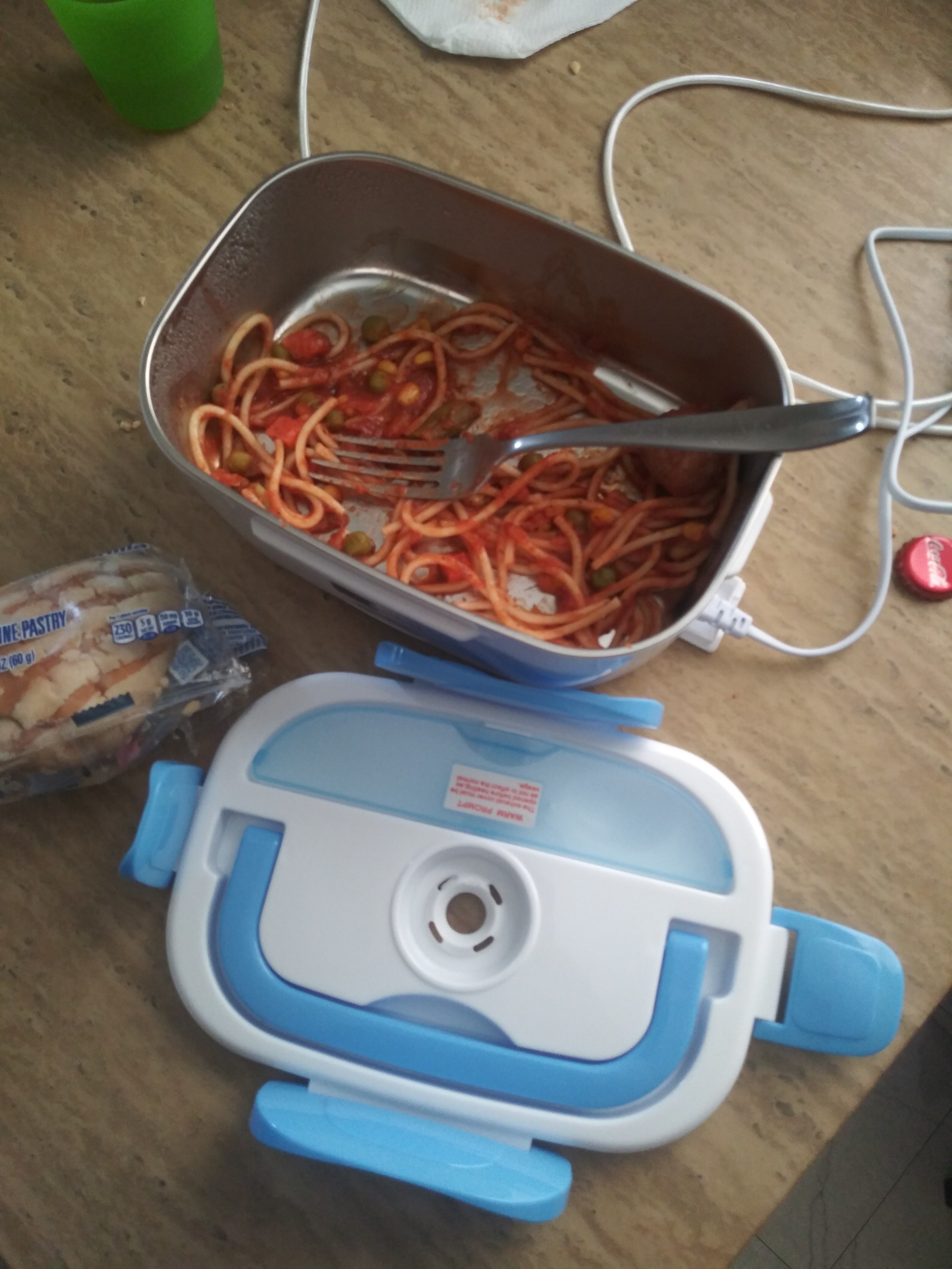 A reviewer&#x27;s blue and white electric lunch box with spaghetti in it that appears to be plugged in