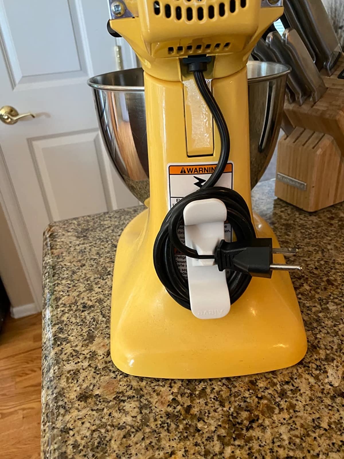 A reviewer&#x27;s yellow stand mixer with the cord organizer on the back and the cord neatly wrapped around it