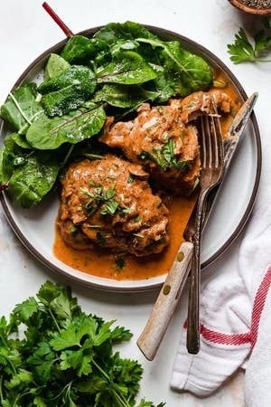 Chicken Thighs With Shallots in Red Wine Vinegar on a plate with greens