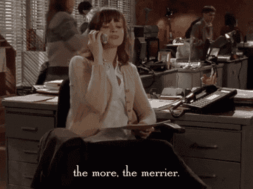 a gif of Rory in &quot;Gilmore Girls&quot; talking on the phone and saying &quot;the more, the merrier&quot;