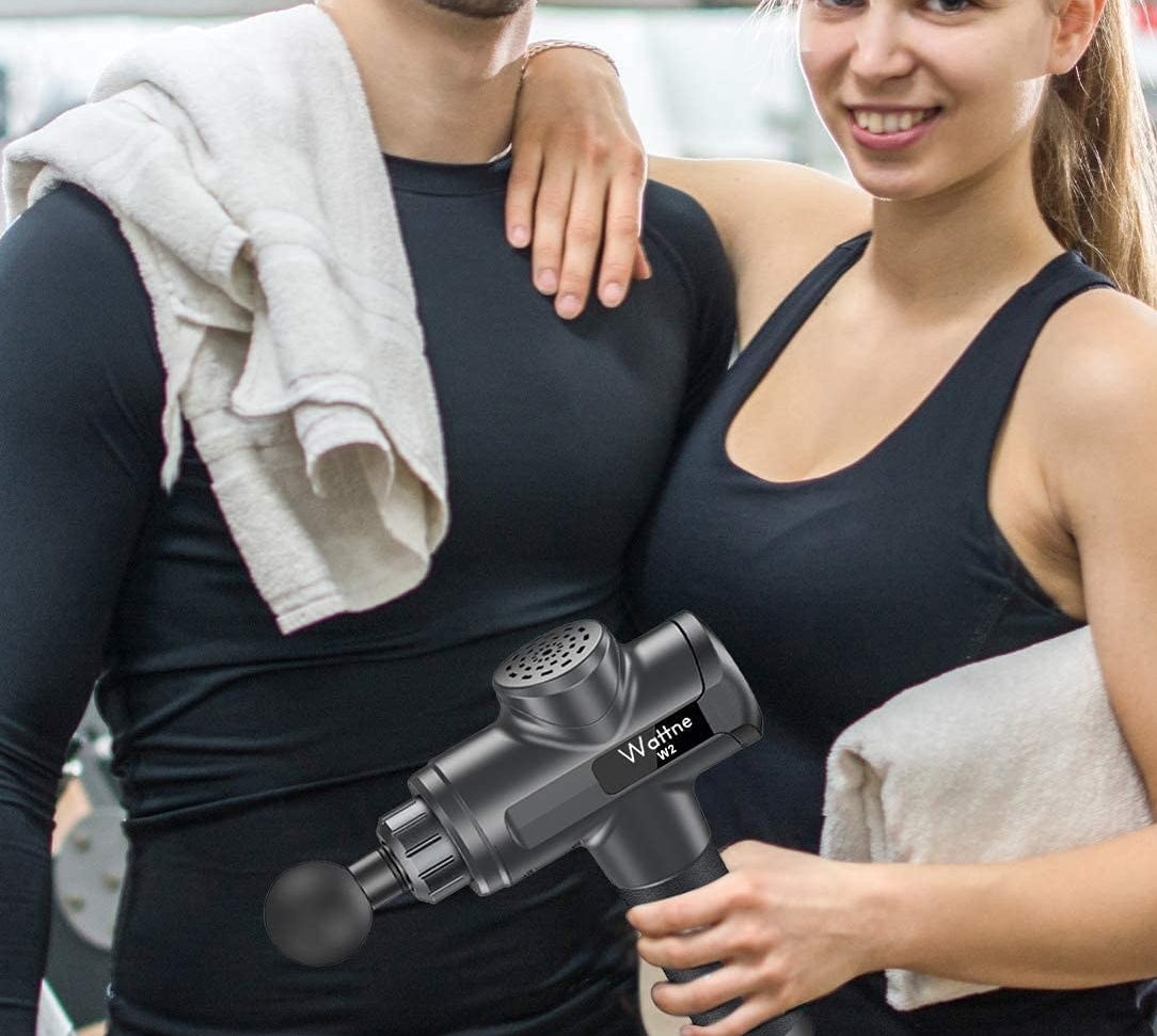 two people holding a massage gun in a gym