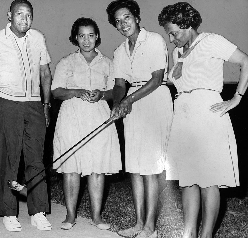 Gibson in the middle of other Black people holding a golf club