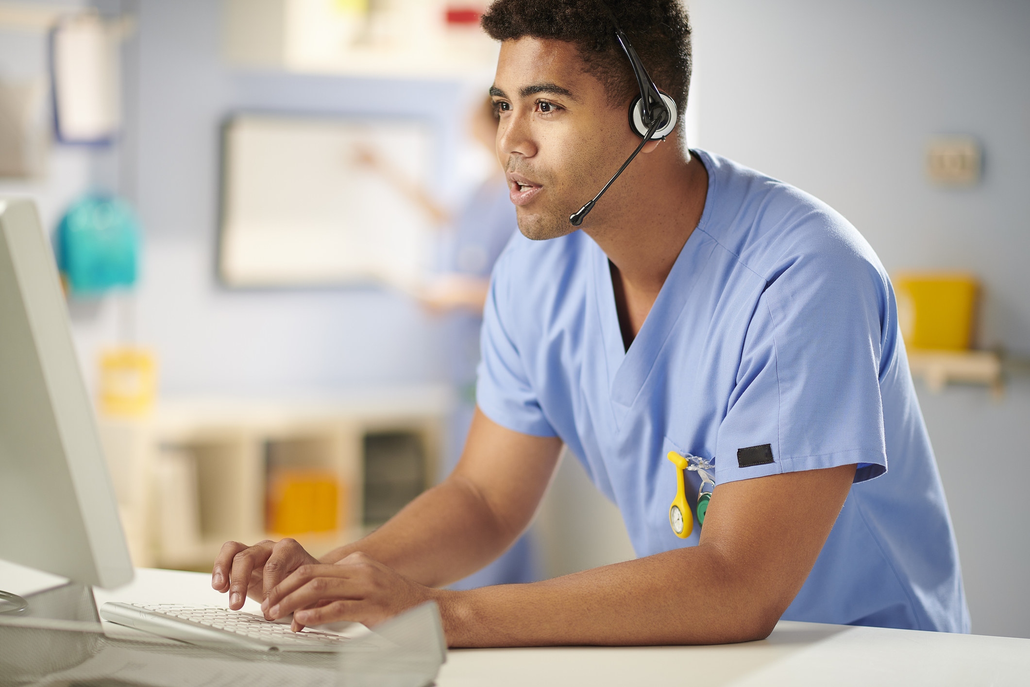 a medical worker on the phone and typing on a computer