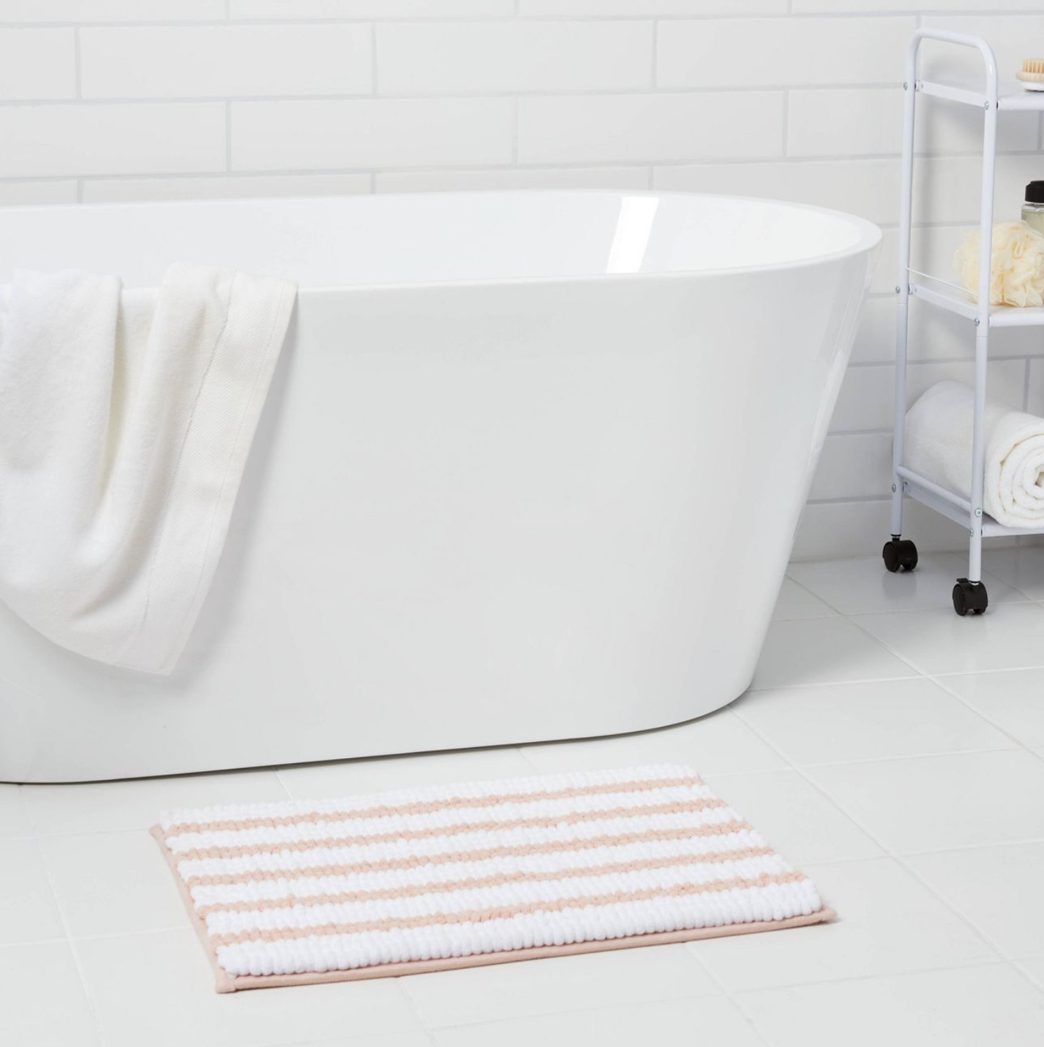 the pink and white striped rug in front of a bathtub