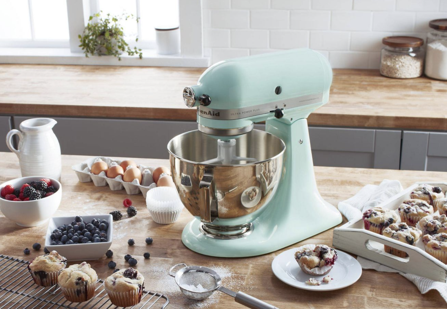 the teal mixer on a table with baked goods around it