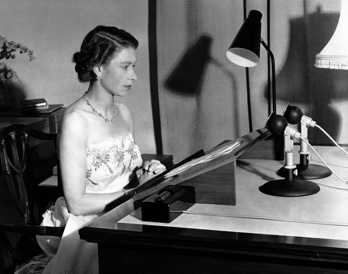 Elizabeth in a strapless gown sitting and giving a radio address