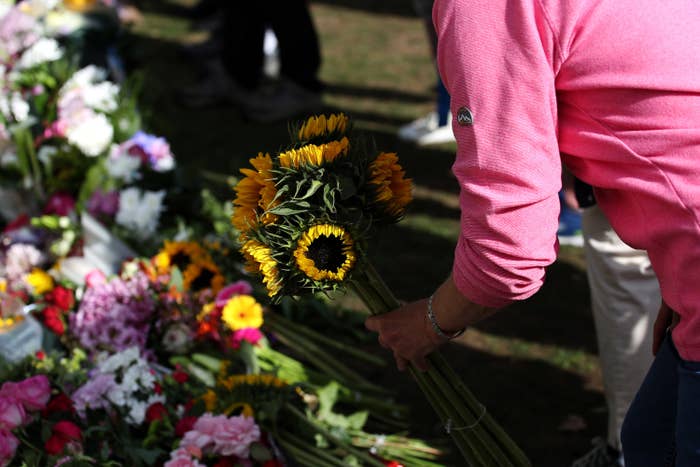 Someone sets down sunflowers on a pile of other flowers