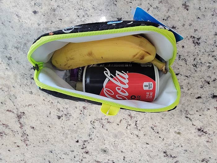 A reviewer&#x27;s small freezer snack bag with an 8 oz coke, banana, and a few more snacks underneath