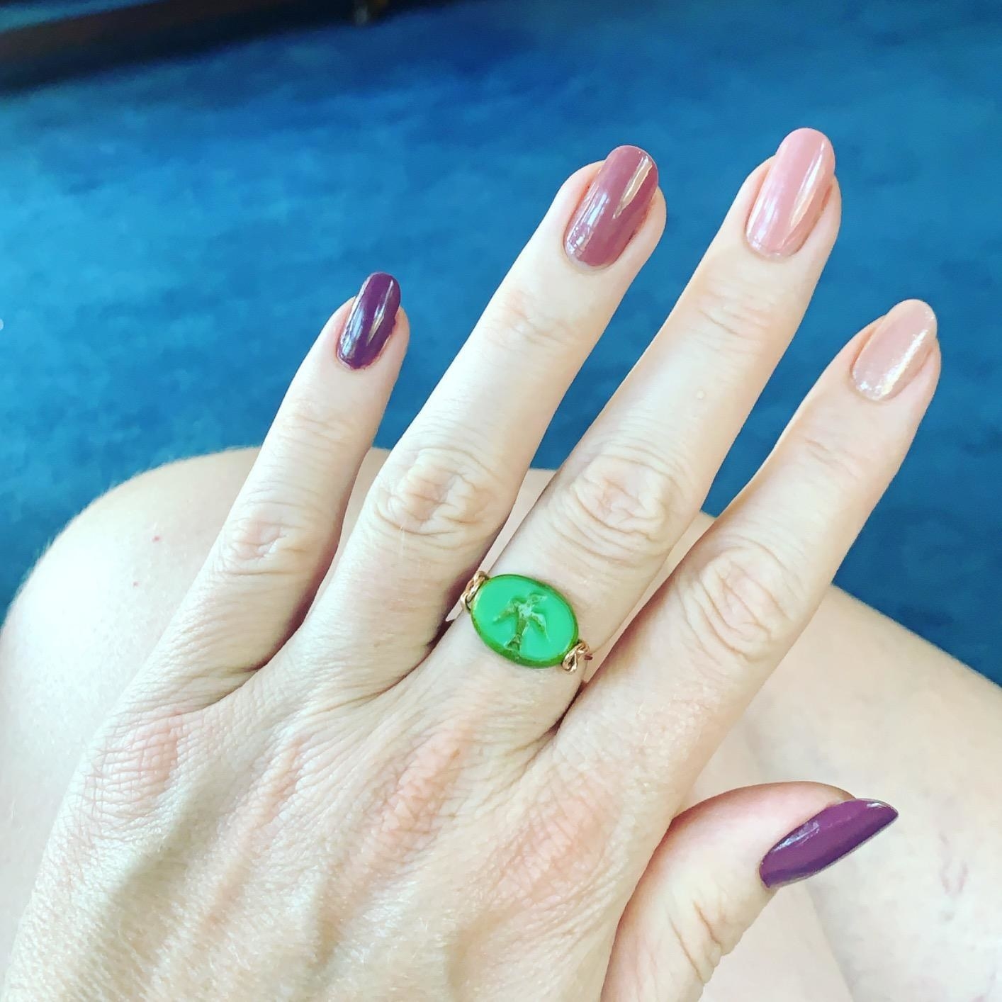 a reviewer photo of a hand wearing all four polishes, with a green ring on the middle finger