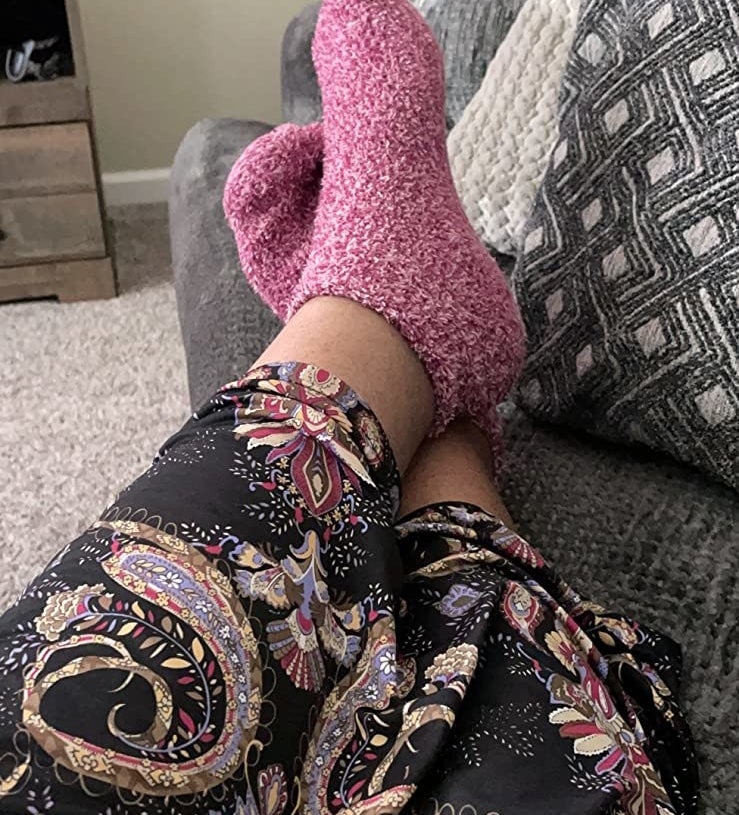 a reviewer photo of a person in a patterned skirt wearing the pink fuzzy socks