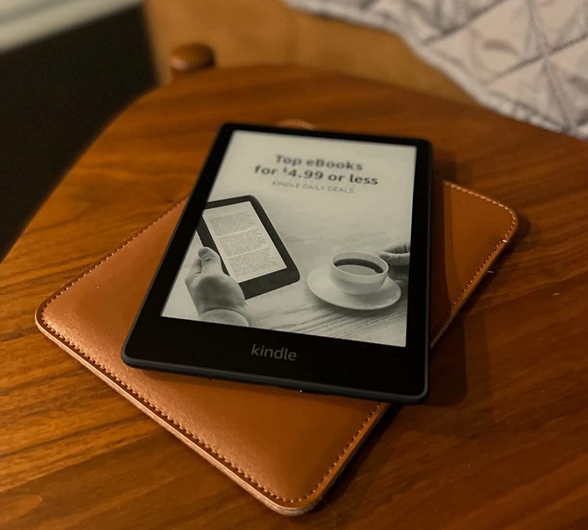 a reviewer photo of the black kindle on top of a leather case on a table