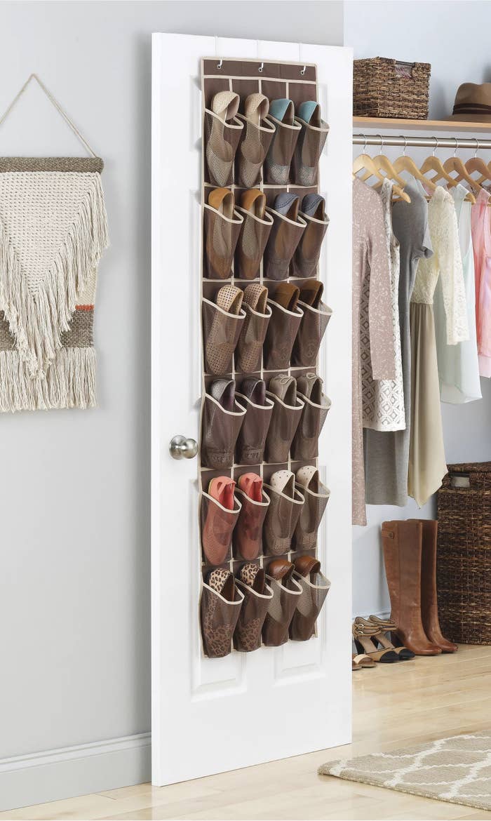 A brown overdoor shoe organizer holding twelve different shoes over a white door