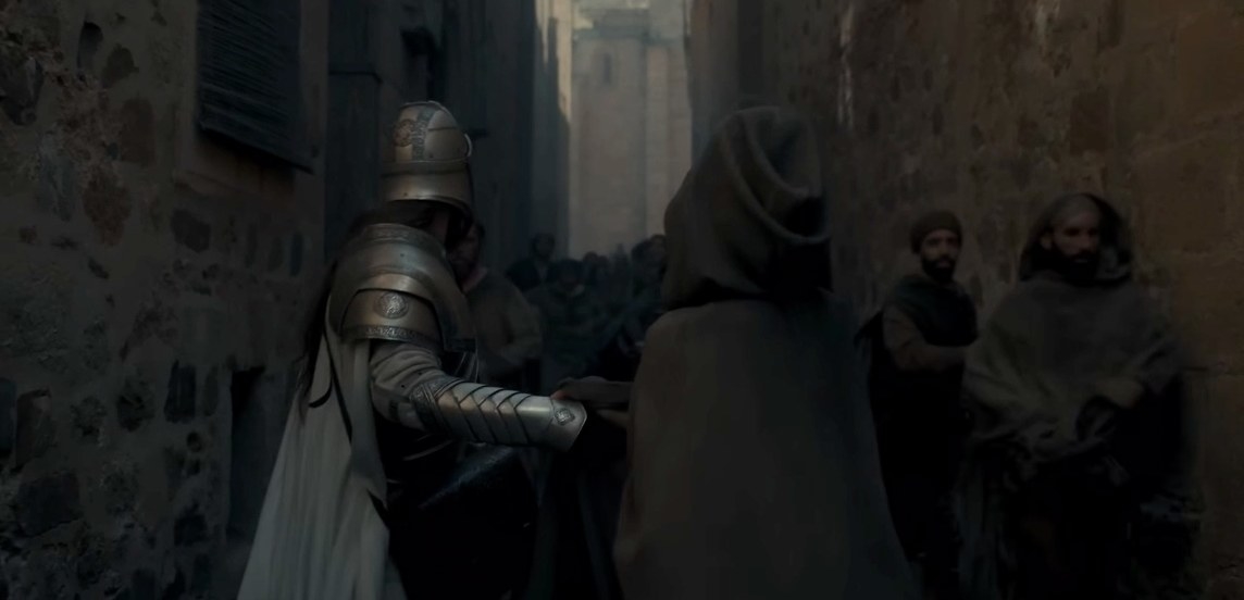 A Kingsguard knight and a hooded figure stand in a King&#x27;s Landing alleyway facing a crowd.