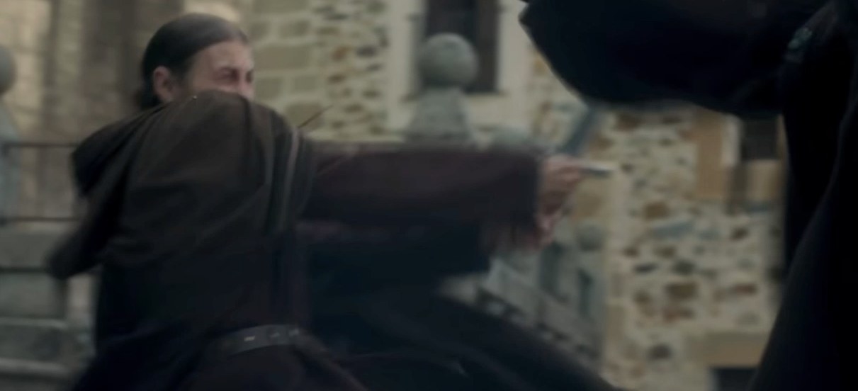 A Kingsguard knight in a plain brown cloak fights someone with his sword