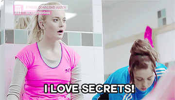 A young woman in a public bathroom says &quot;I love secrets!&quot; to another one