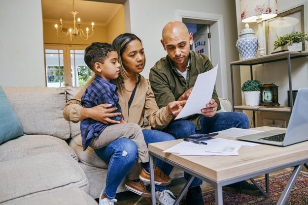 A couple evaluates their finances in their family room while their son sits with them