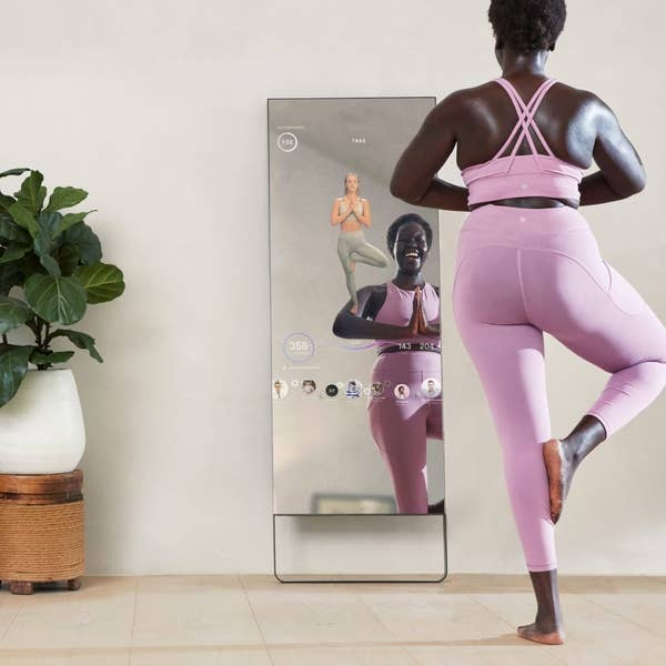 model in pink workout set completing yoga workout with the Mirror interactive training hub