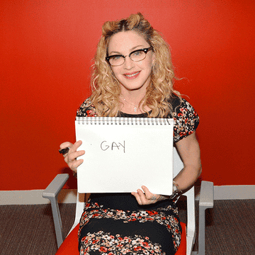 Madonna holding up a spiral notebook with &quot;GAY&quot; written on a page