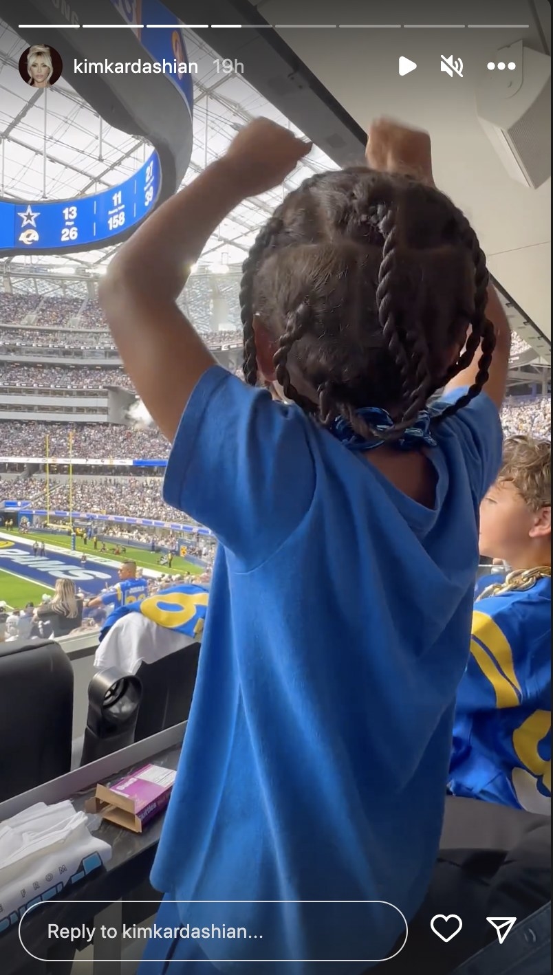 Saint holds his arms up and cheers while watching the game