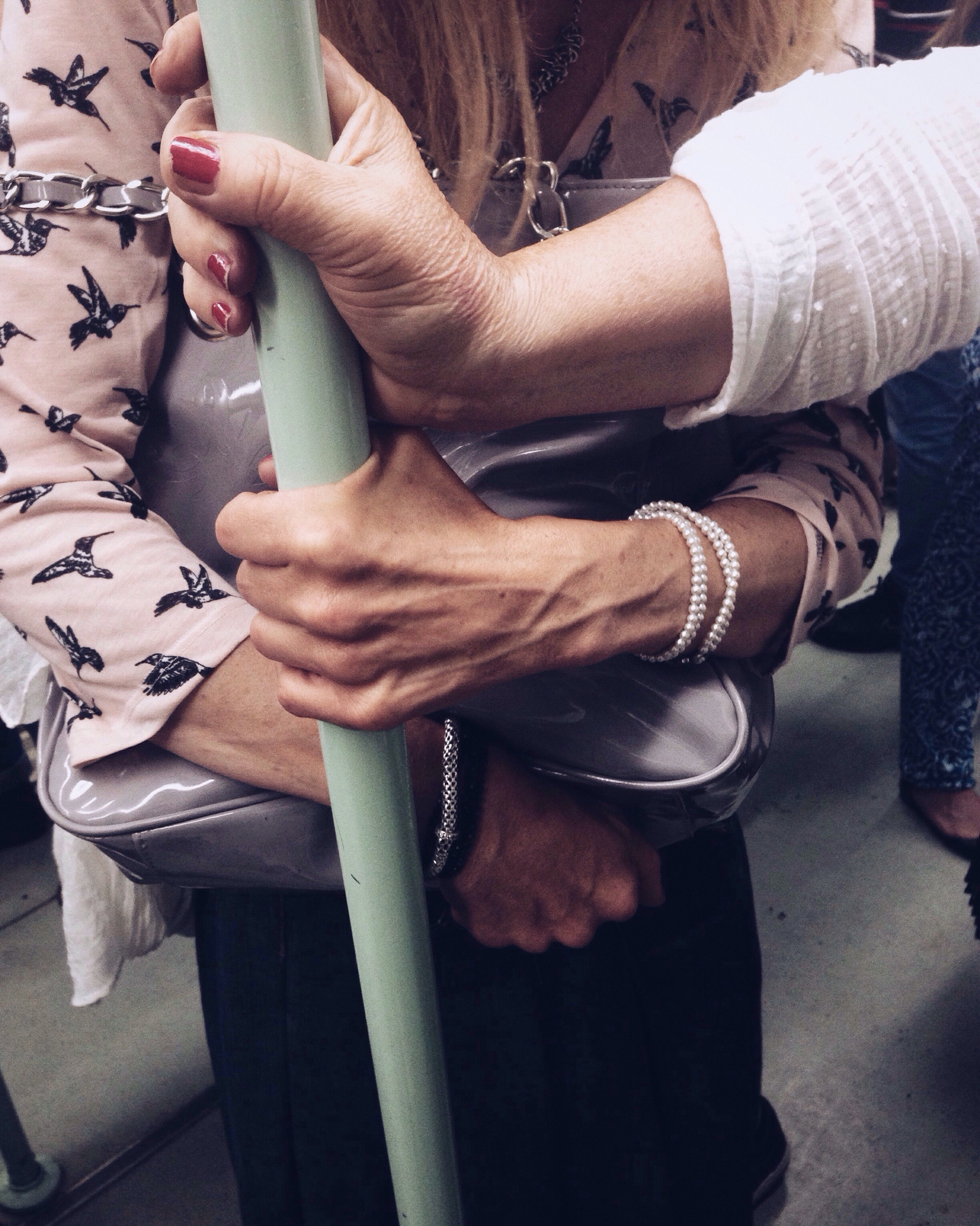 A woman clutching her handbag while holding onto a pole on a train