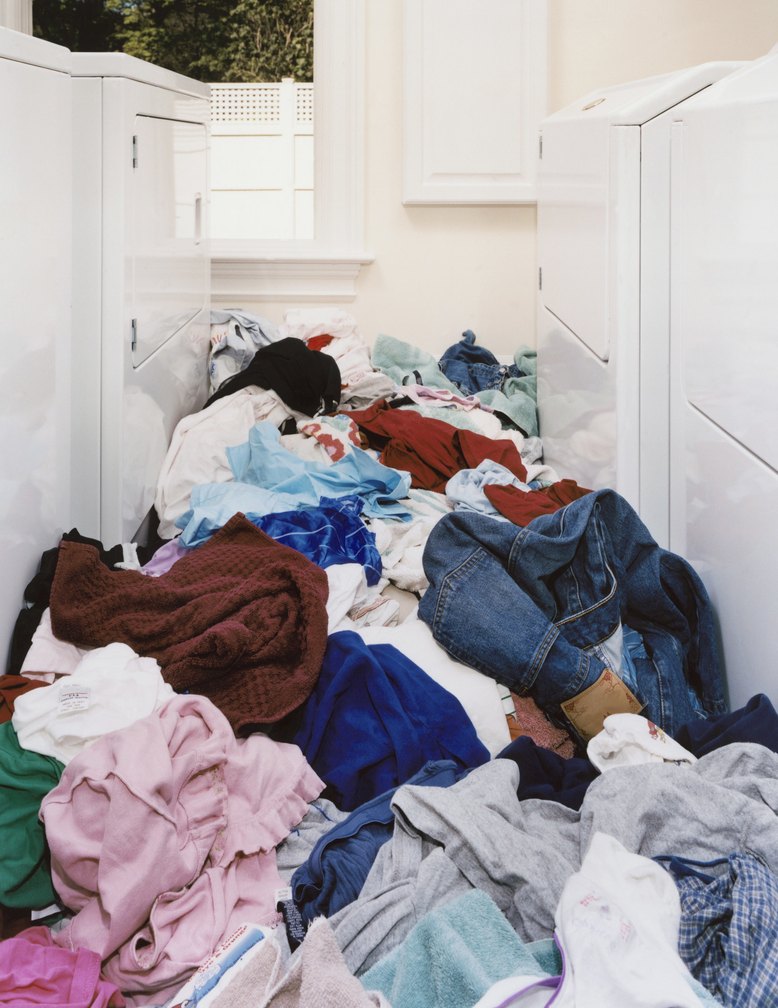 A laundry room with a knee-deep pile of laundry