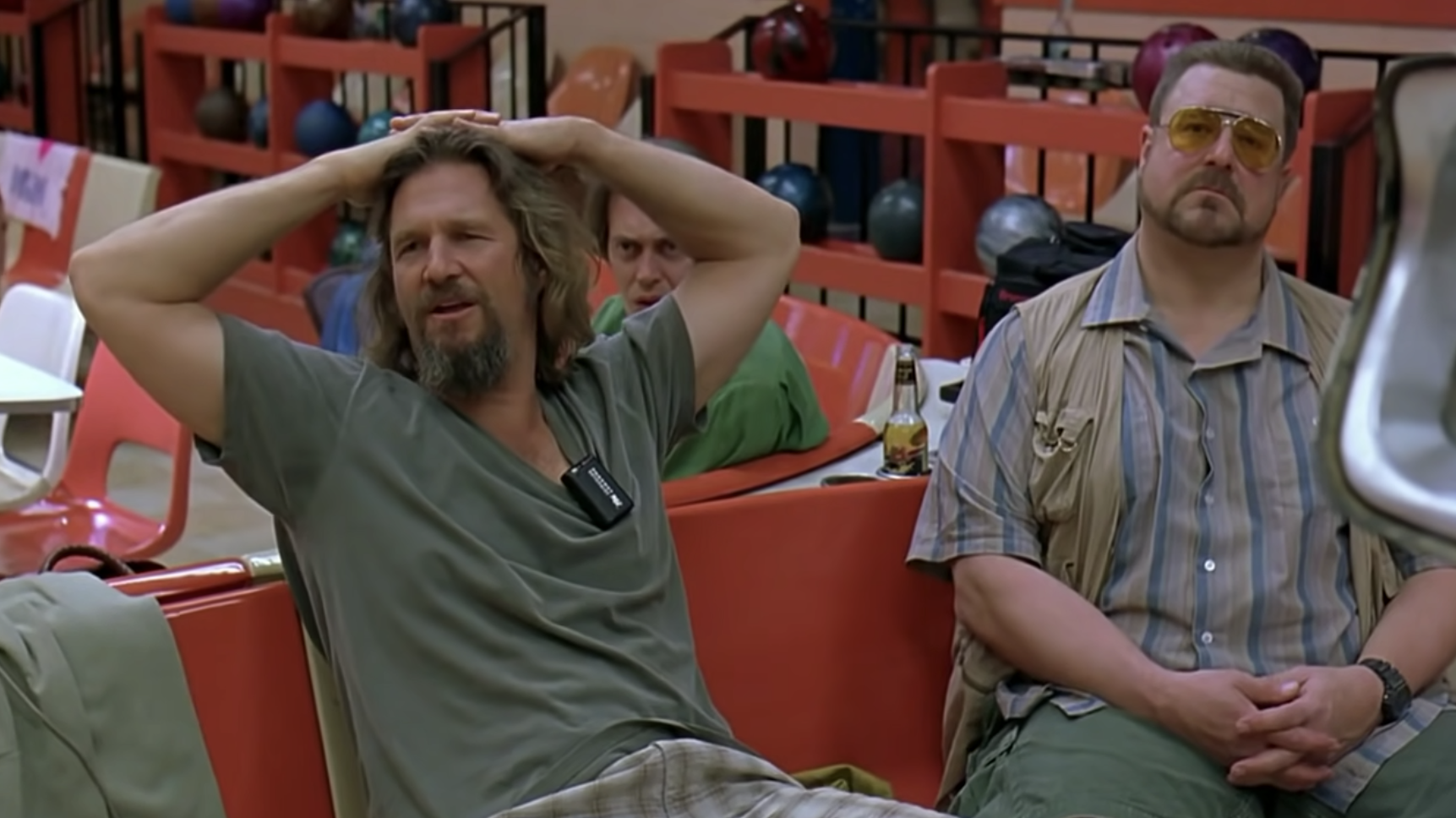 two men sitting down at a bowling alley