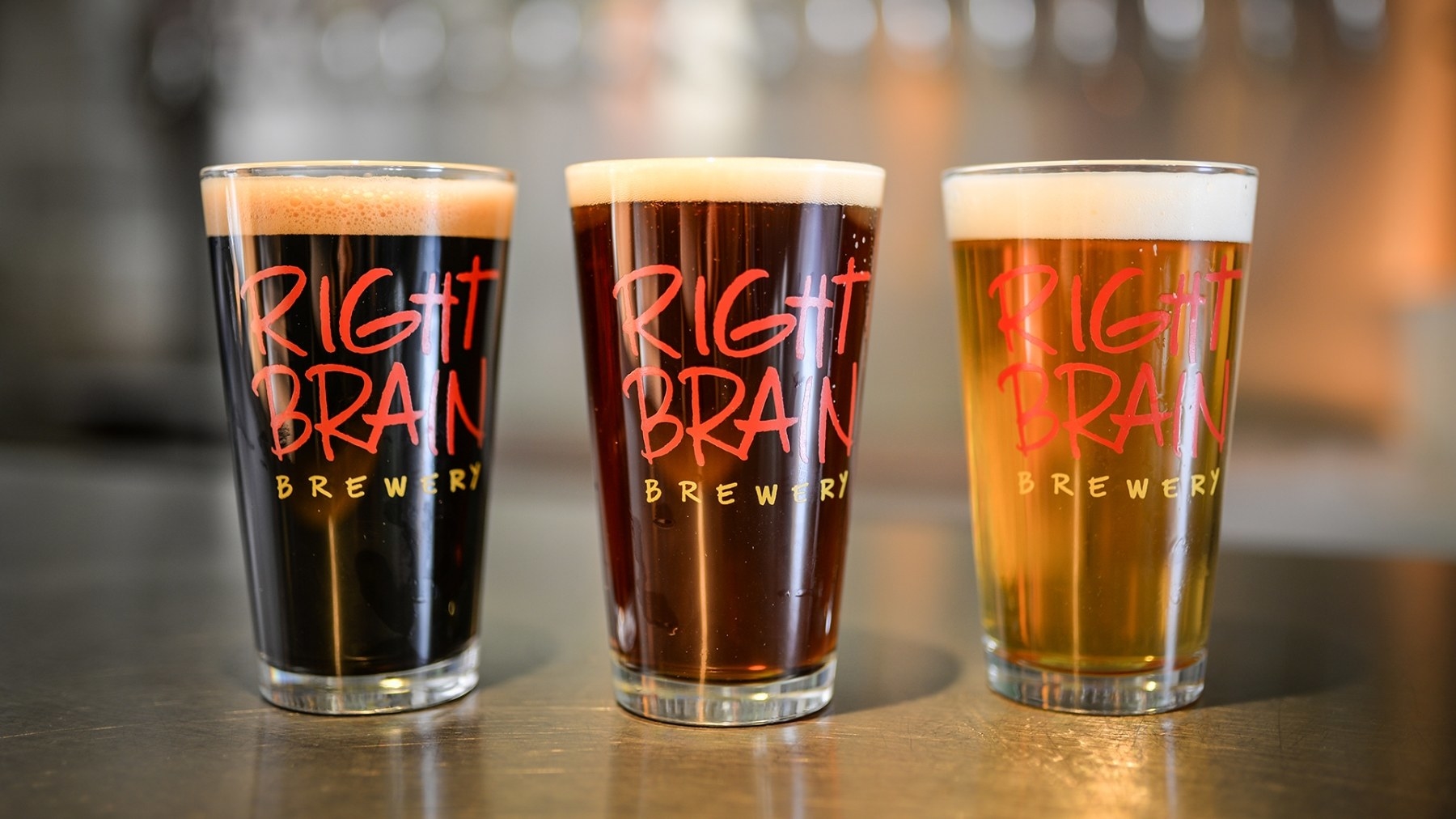 Three glasses holding differently colored beers, ranging from dark to light