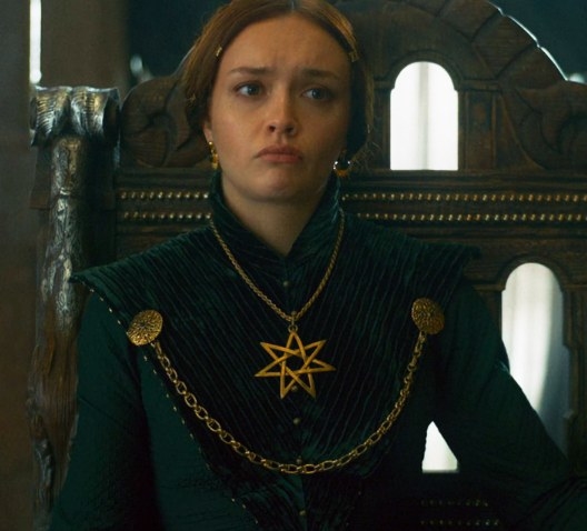 Alicent wears a conservative green gown with a large seven-pointed star necklace and her hair tied up