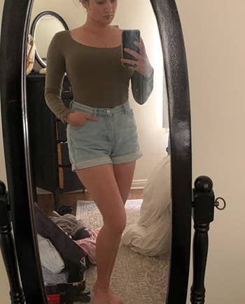 reviewer wearing the green bodysuit with denim shorts