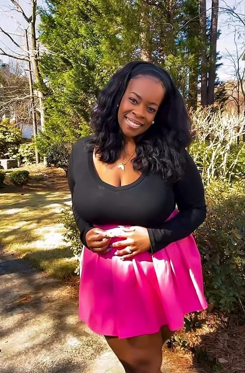 reviewer wearing the bodysuit in black with a pink skirt
