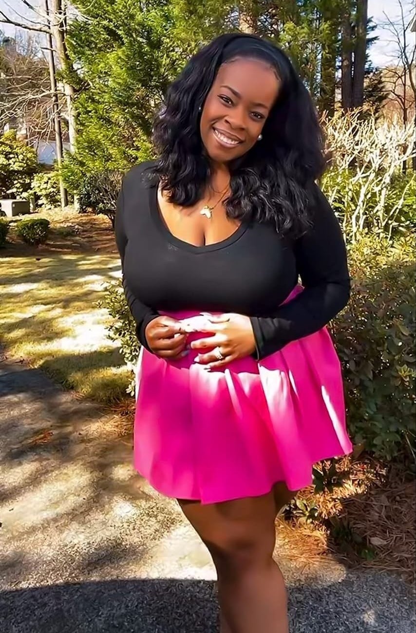 reviewer wearing the bodysuit in black with a pink skirt