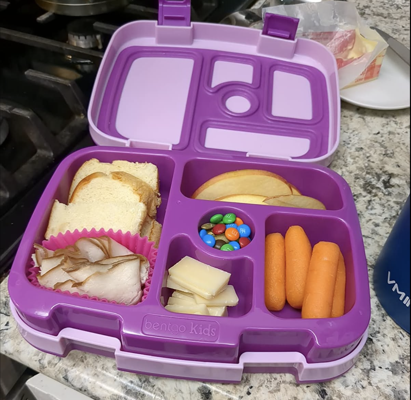 purple lunchbox with five differently shaped sections for fruits, veggies, cheese, and. a sandwich